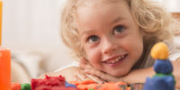 Lovely portrait of a little girl with big eyes, playing with colourful clay